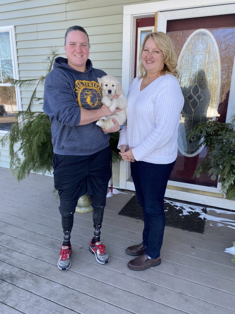 Two women standing with Service Dog in Training Abigail.