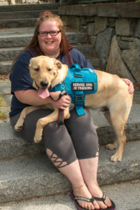 Katelyn Spencer, MWD Event Coordinator, sitting on steps holding a yellow lab